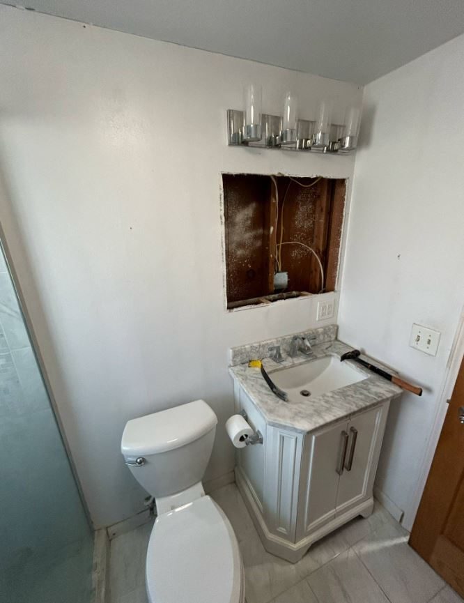 New vanity with a marble-look top installed while the wall above is still open for lighting work